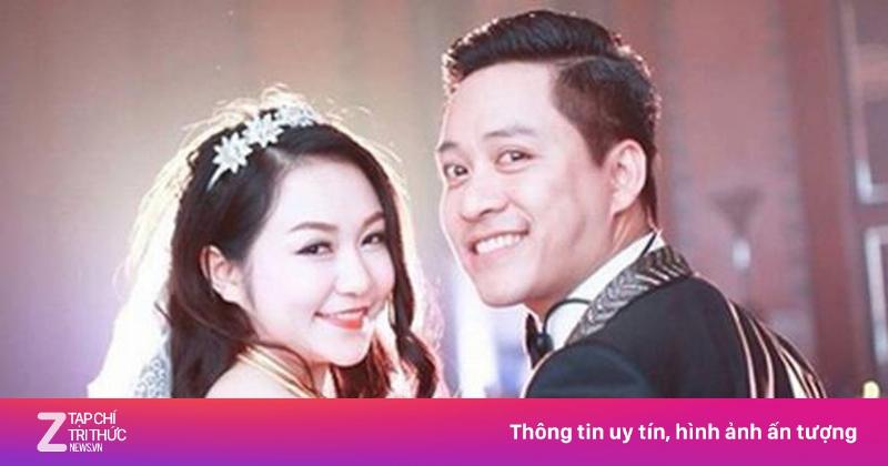 Cô dâu mặc váy cưới trắng, tay cầm bó hoa sen, nở nụ cười hạnh phúc trong lễ cưới.