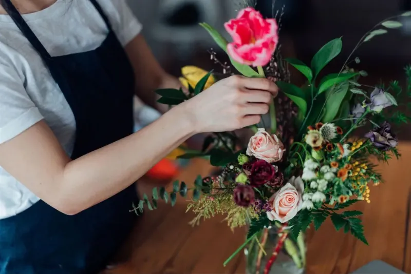 Một lẵng hoa lớn kết hợp bông hồng vàng với các loại hoa lá khác, đặt ở sảnh đón khách