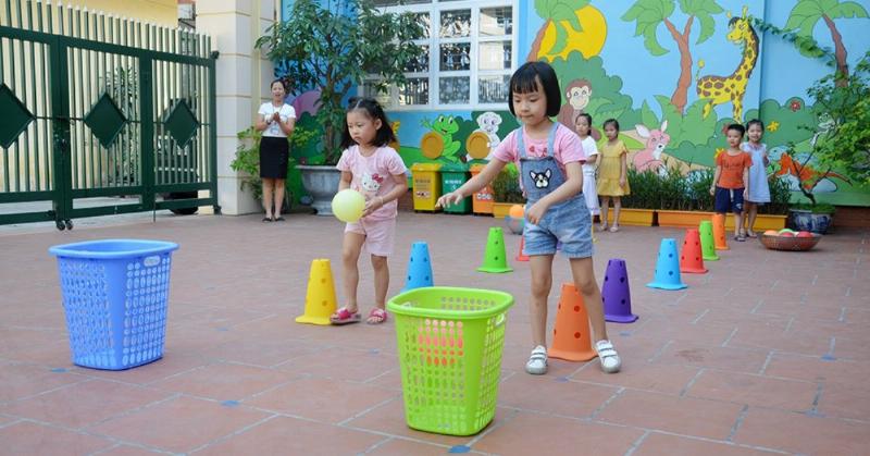Hình ảnh một gia đình gồm cha mẹ và một em bé khoảng lớp 3 đang cùng nhau chăm sóc một chậu cây nhỏ trong nhà, tượng trưng cho sự gắn kết và nuôi dưỡng tình yêu thương trong gia đình.