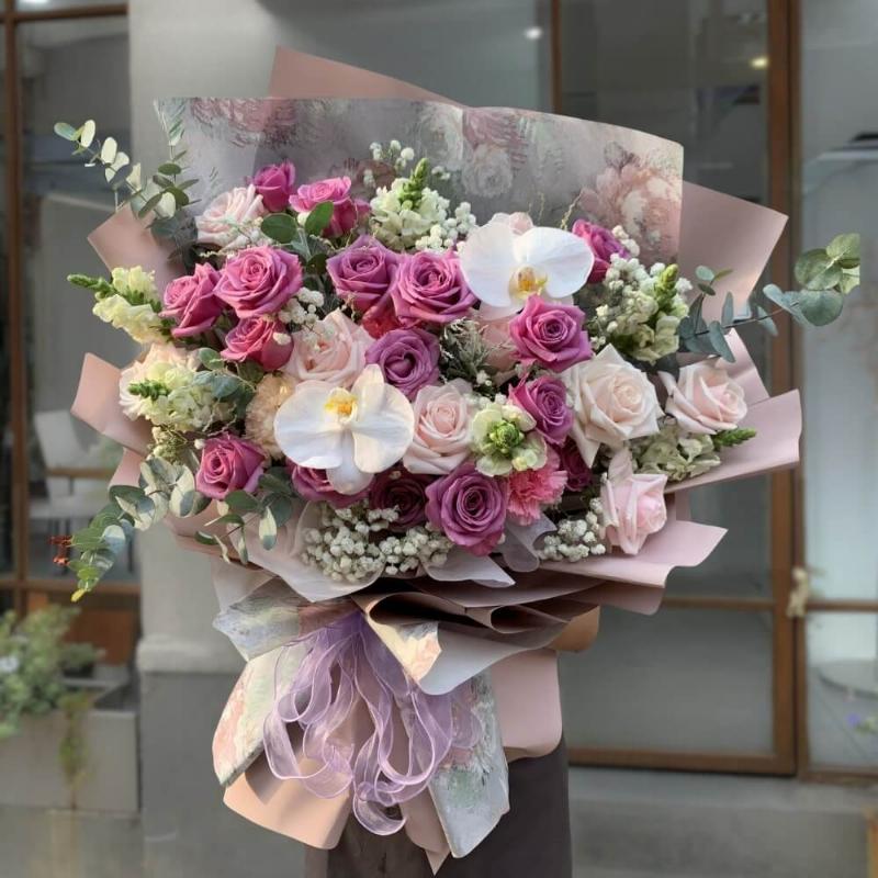 Một bó hoa sinh nhật được gói kỹ lưỡng với hoa hồng trắng, lan hồ điệp tím nhẹ và một vài cành baby trắng, thể hiện sự sang trọng và tinh tế cho ngày 30/9 