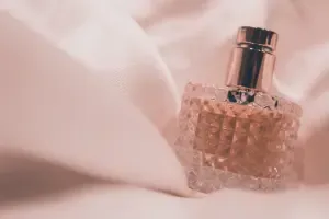 Một chai nước hoa với thiết kế tinh tế màu hồng, gợi nhớ hương thơm quyến rũ của hoa lài, đặt trên nền vải mềm mại.
