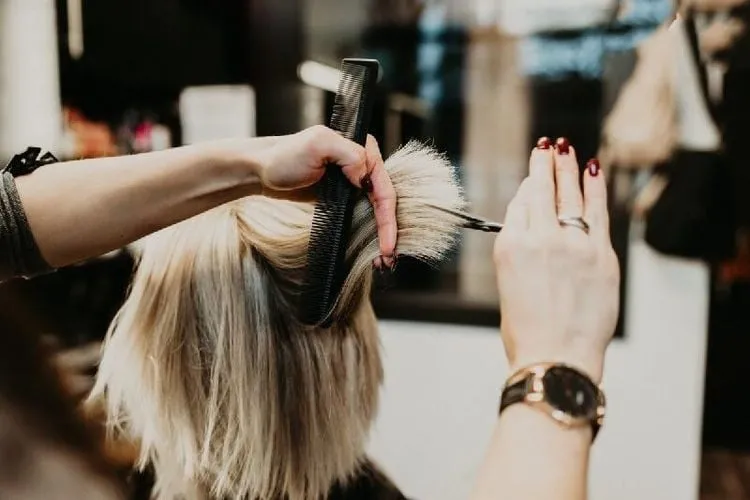 Kéo tỉa tóc trên ngọn tóc, biểu thị việc cắt tỉa đều đặn để loại bỏ tóc chẻ ngọn và thúc đẩy tóc dài.
