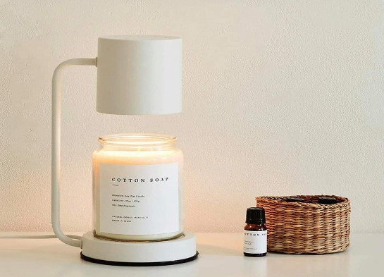 Đèn đốt nến đang làm tan chảy một hũ nến thơm lớn, tỏa ánh sáng vàng ấm áp