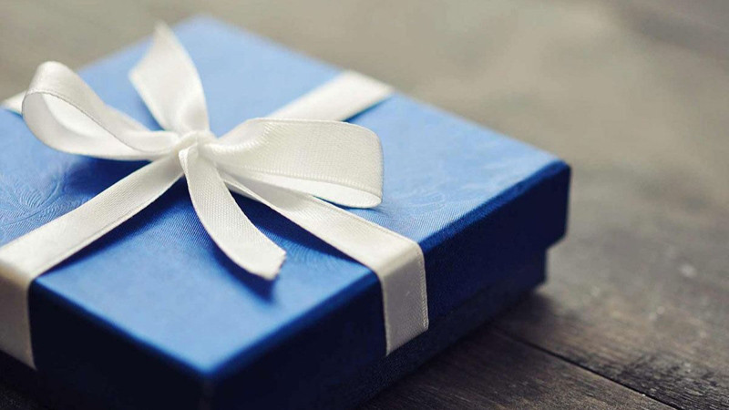 Món quà được gói cẩn thận với ruy băng, đặt cùng tấm thiệp