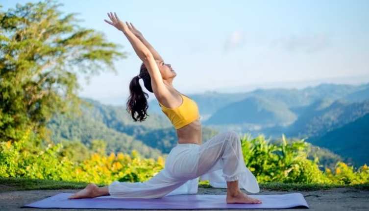 Một người phụ nữ trẻ đang thực hiện tư thế yoga trên bãi biển vào buổi sáng