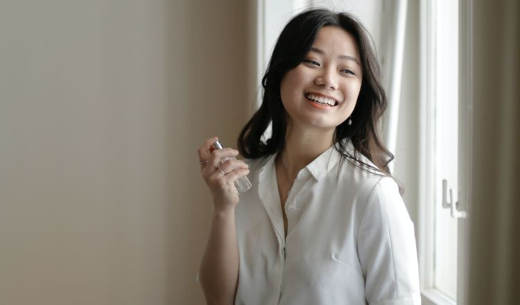 Người đang xịt nước hoa lên lược chải tóc bằng gỗ trước khi sử dụng