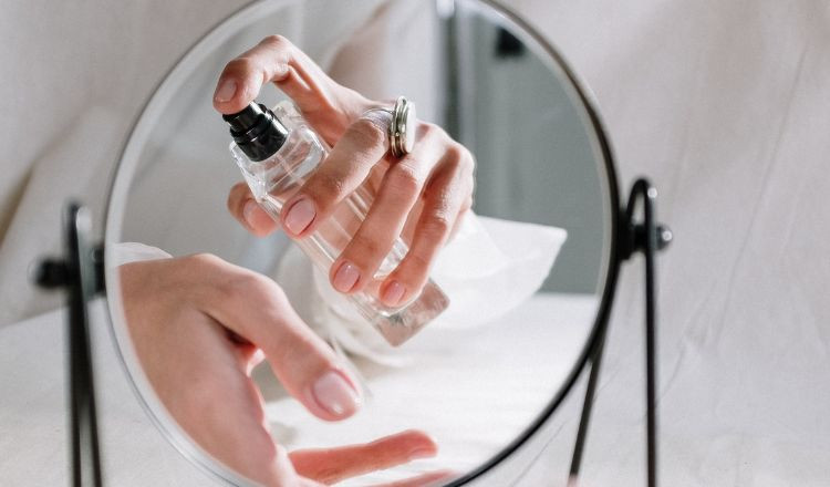 Người phụ nữ đang xịt nước hoa vào vùng cổ sau khi tắm xong